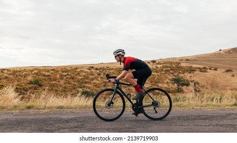 Side View Of Young Woman Cyclist Riding On Bicycle Against Hill