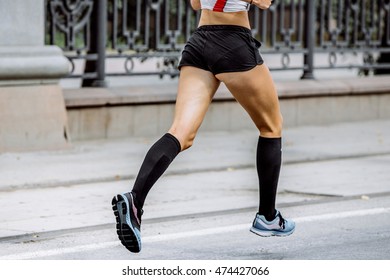 Side View Of Young Woman Legs In Compression Socks Athlete Running A Marathon