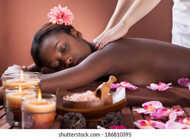 Side view of young woman receiving shoulder massage at spa salon