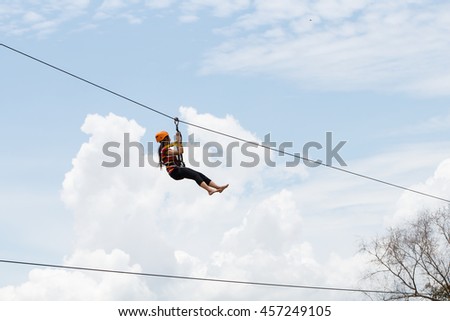 side view of young woman riding on zip line against sky