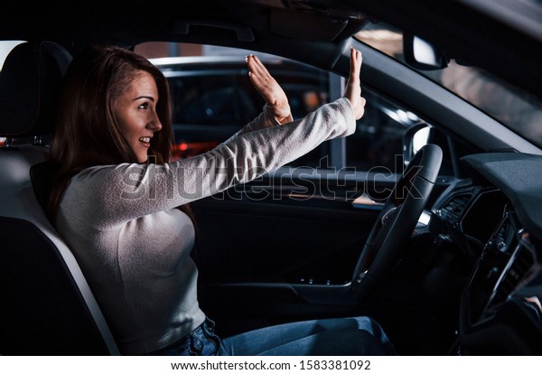 Side view of young woman that inside of brand
new modern automobile.