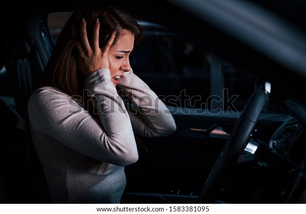 Side view of young woman that gestures inside\
of brand new modern\
automobile.