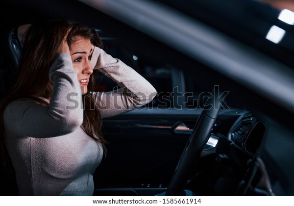 Side view of young woman that gestures inside\
of brand new modern\
automobile.