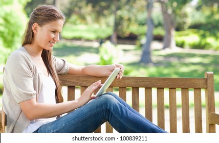 Side view of a young woman using a tablet computer on a park bench - Powered by Shutterstock