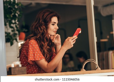 side view of young woman using smartphone in cafe