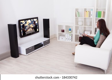 Side View Of Young Woman Watching TV In Living Room