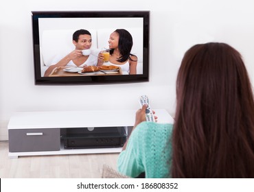 Side View Of Young Woman Watching TV In Living Room