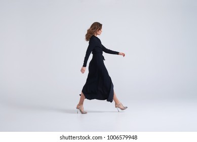 Side View Of Young Woman Wearing Long Black Dress Walking