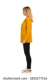 Side View Of Young Woman In Yellow Jacket, Black Jeans And Colorful Sneakers. Full Length Studio Shot Isolated On White.