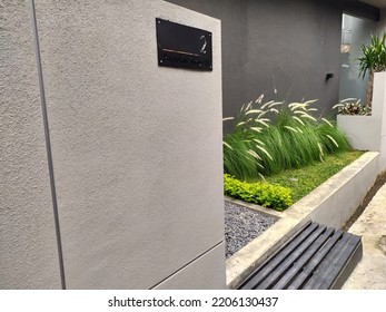 The Side Yard Of A Simply Modern Minimalist House. There Is A Small Garden Planted With Weeds And Green Grass