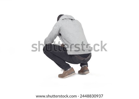 side,back view of man squatting and looking down on white background