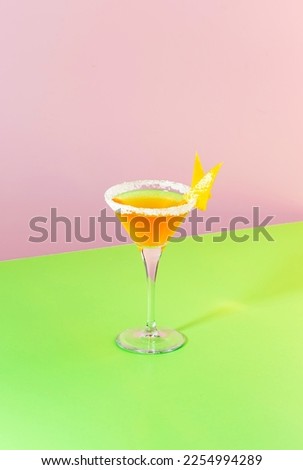 Sidecar alcoholic cocktail with cognac, liqueur, lemon juice and ice. Pink and green pop background