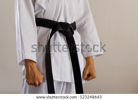side-front view of a karate black belt with clenched fists
