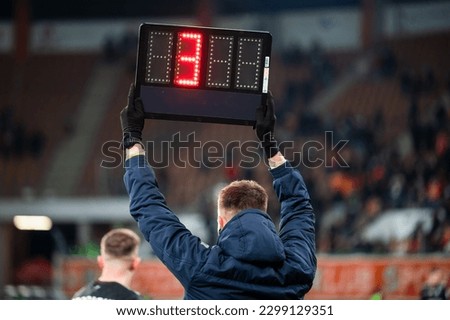 Sideline referee shows 4 minutes added time during the football match.