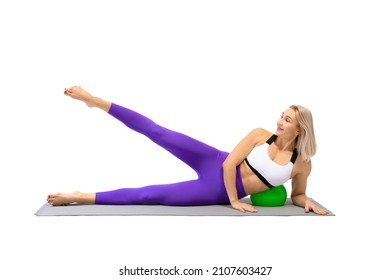 Side-lying leg circles drill. Fit caucasian woman practice pilates using a small fit ball as a support, isolated on white.
