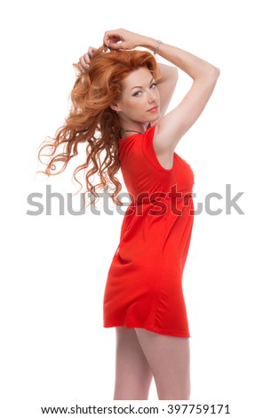Sideshot of a redhead in a red dress with arms raised.