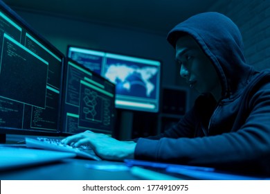 Sideview of asian male hacker use computer to commit a crime