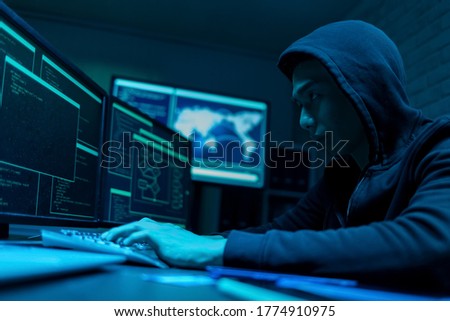 Sideview of asian male hacker use computer to commit a crime