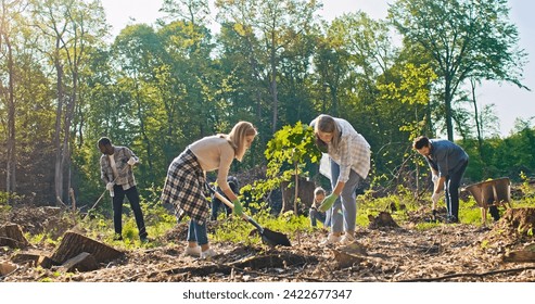 Side-view of charming middle-aged Caucasian woman holding and planting trees with beautiful young woman digging with shovel. Team of volunteers doing reforestation work in forest. - Powered by Shutterstock