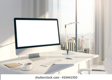 Sideview Of Creative Desktop With Blank White Computer Screen In Sunlit Office With Windows And City View. Mock Up, 3D Rendering