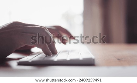 Sideview of a man's hand typing on a computer keyboard, busy with Internet browsing and email. Secretary diligently managing information tasks at office work.