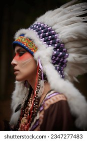 Sideview portrait of an American Indian girl in a national costume and headdress on a black background. Ethnic American culture.