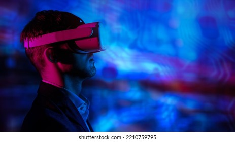 Sideview Portrait Of A Businessman In Virtual Reality Glasses In The Neon Light. Modern Information Technologies. Copy Space.