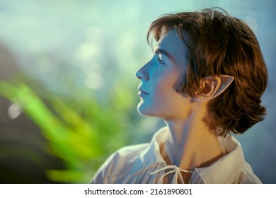 Sideview shot of a handsome fairy elf boy in a beautiful forest. Fantasy. Fairy tale, magic. 