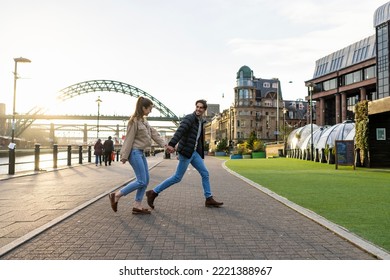 A side-view shot of a young couple walking side by side together, they are holding hands and they're in love. - Powered by Shutterstock