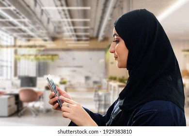 Sideview of woman using mobile smart cell phone browsing or app concept wearing Abaya and Hijab traditional women's clothing. Side shot of girl in Shayla headscarf