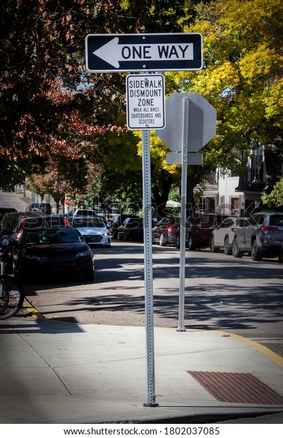 Sidewalk Dismount Zone for bikes and scooters sign\
on busy shaded autumn\
street