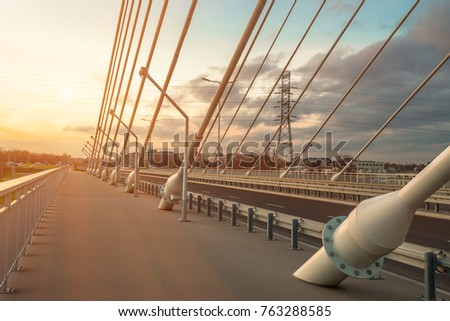 Similar – Image, Stock Photo Suspension bridge with steel cables spanning a frozen river against a backdrop of snow-covered mountains at dusk