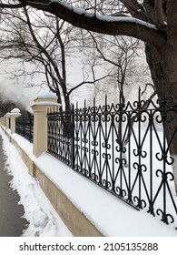 Sidewalk And Iron Fence In Winter With Steam In The Background. White Steam From A Burst Hot Water Pipe In Winter. 