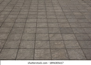 The sidewalk is paved with square decorative tiles.