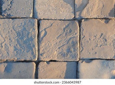 The sidewalk is paved with square paving stones
