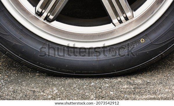 Sidewall of the  car tire with a low tire pressure on\
the road,close up