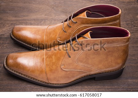 Sideways brown chukka boots on a wooden floor