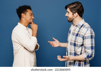 Sideways young two friends smiling happy cheerful fun cool men 20s wear white casual shirts talk speak together isolated plain dark royal navy blue background studio portrait People lifestyle concept