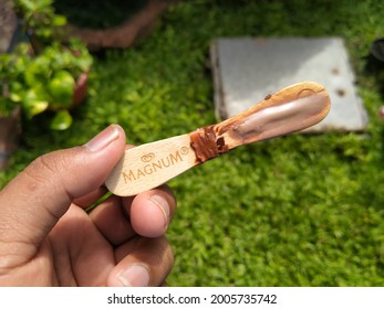 Sidoarjo, Indonesia - July 10, 2021: Hand Holding A Leftover Stick Of Magnum Brand Ice Cream On A Green Plant Background.