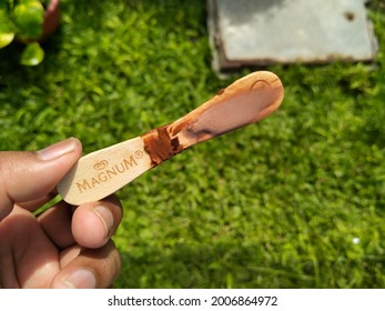 Sidoarjo, Indonesia - July 10, 2021: Hand Holding A Leftover Stick Of Magnum Brand Ice Cream On A Green Plant Background.