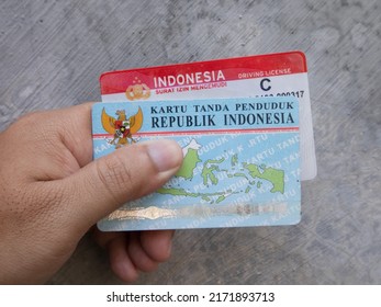  Sidoarjo, Indonesia - June 27, 2022 : A Man Holding Two ID Cards And A Sim Card On A Blurred Gray Background