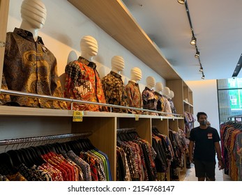 Sidoarjo, Indonesia - May 6, 2022: A man is choosing batik shirts to buy in a batik shop. Batik clothes on display in a boutique.