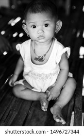 Siem Reap, Cambodia - December 9th 2018: Black and white portrait of a young girl in her stilted house