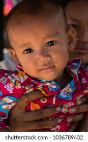 Siem Reap, Siem Reap Province, Cambodia - November 27 2015 : Close up portrait of a young smiling baby in colourful pyjamas under a shaded canopy in a village on Highway 6 close to Siem Reap