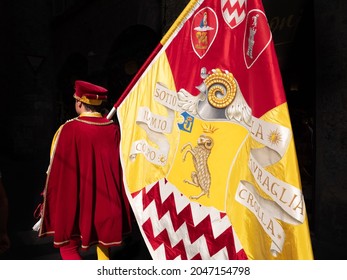 Siena, Italy - August 15 2021: Standard Bearer or Flag Bearer of the Shell or Seashell Contrade, a Page bearing the Banner of the Nobile Contrada del Nicchio and wearing 15th-century costumes..