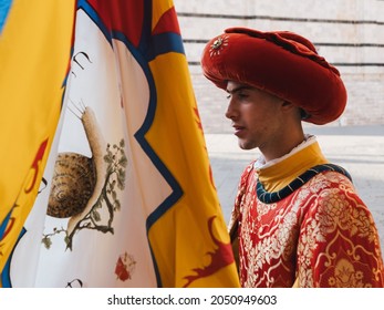 Siena, Italy - August 15 2021: Standard Bearer or Flag Bearer of the Snail Contrade, a Page bearing the Banner of the Contrada della Chiocciola  and wearing 15th-century costumes..