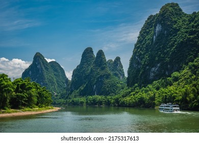 Sightseeing boat carrying tourists sailing among high vertical cliffs of karst mountains on the magnificent Li river flowing between Guilin and Yangshuo towns, China - Shutterstock ID 2175317613