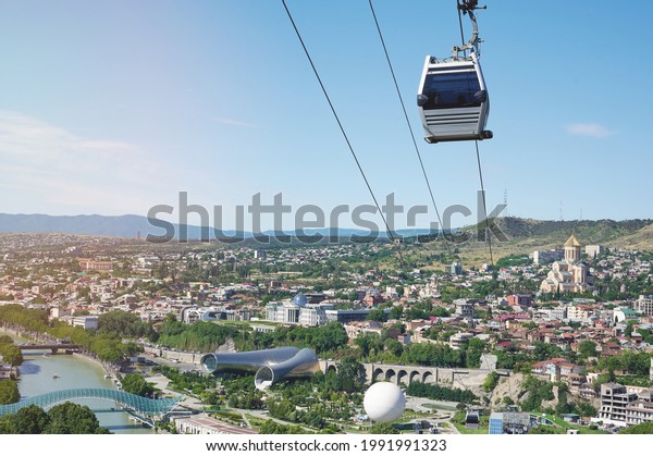 Sightseeing cable car move over Tbilisi city on\
bright sunny day