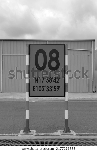 A sign at an airport in a city.  At the base of\
aircraft and roads.  Drawings.  Posters on the side of the road \
back and withe