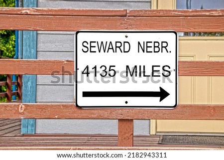 Sign with arrow reading Seward Nebr 4135 miles hanging on railing in Seward Alaska USA